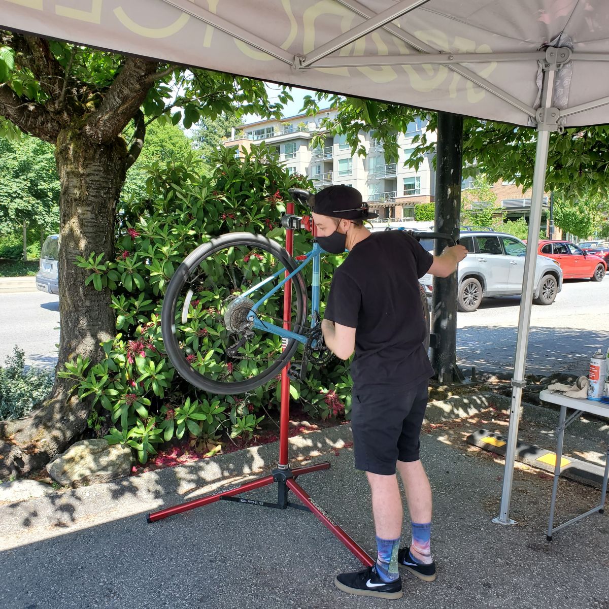 A bike mechanic wearing a mask inspects a bike