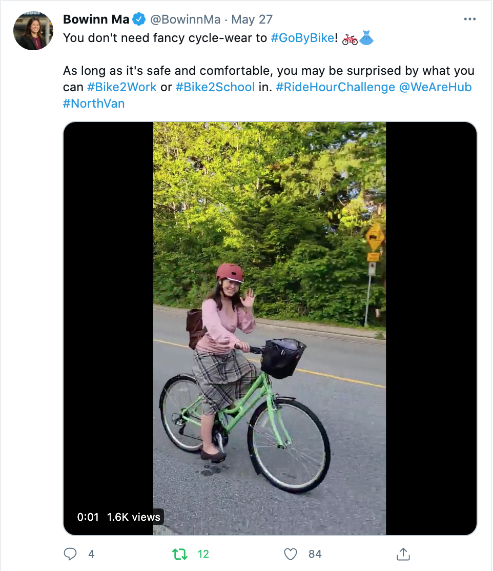 A woman smiles and waves as she rides her bike