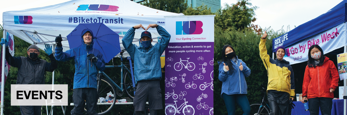 Events. Several people in rain gear stand at one of our Fall Go by Bike Week stations. They are all in good spirits.