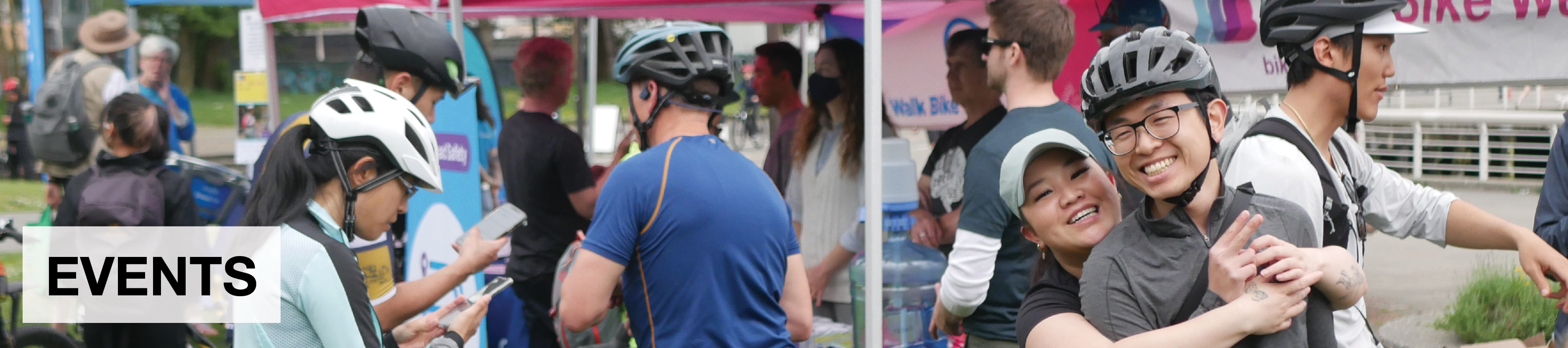 Events. Several people gather in front of several tents at a Go by Bike Week celebration station.