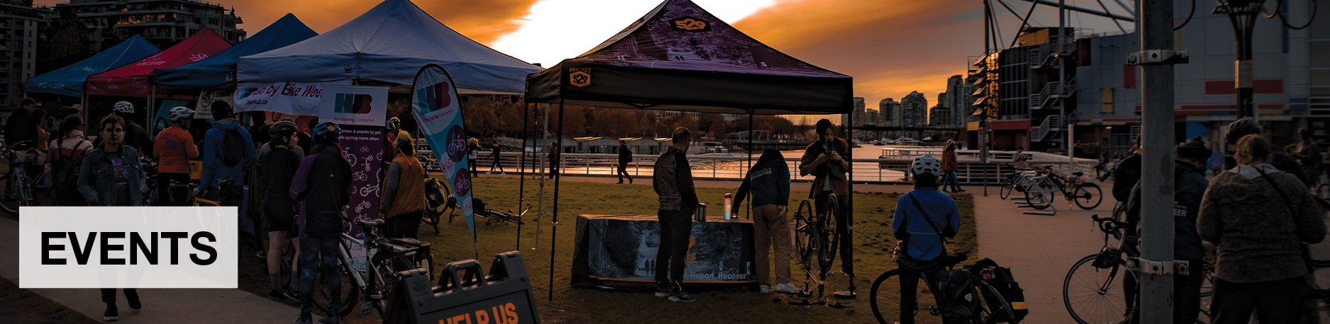 Events. Several people gather in front of several tents at a Go by Bike Week celebration station.