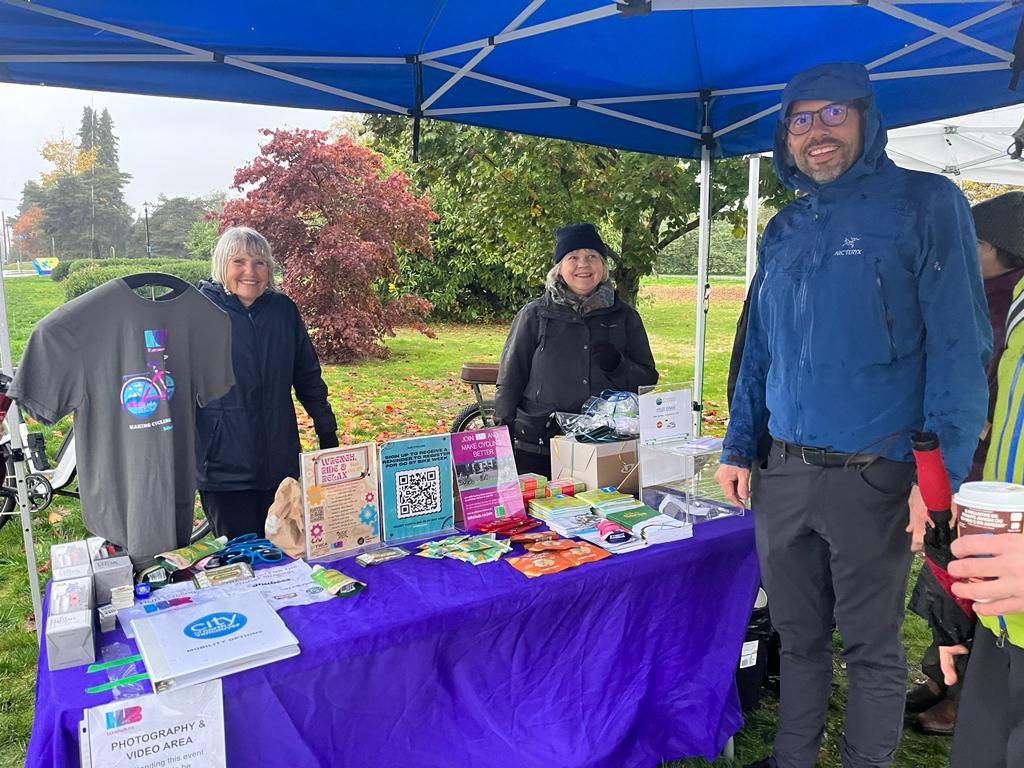 Two women in their 60s and one man in his 40s, all volunteers, stand smiling at a Celebration Station.