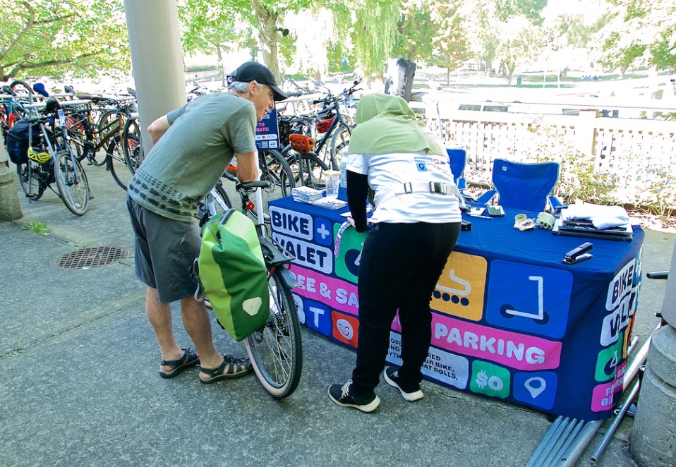 A woman wearing a hijab checks in her bike with a white man in his 50s at the bicycle valet.