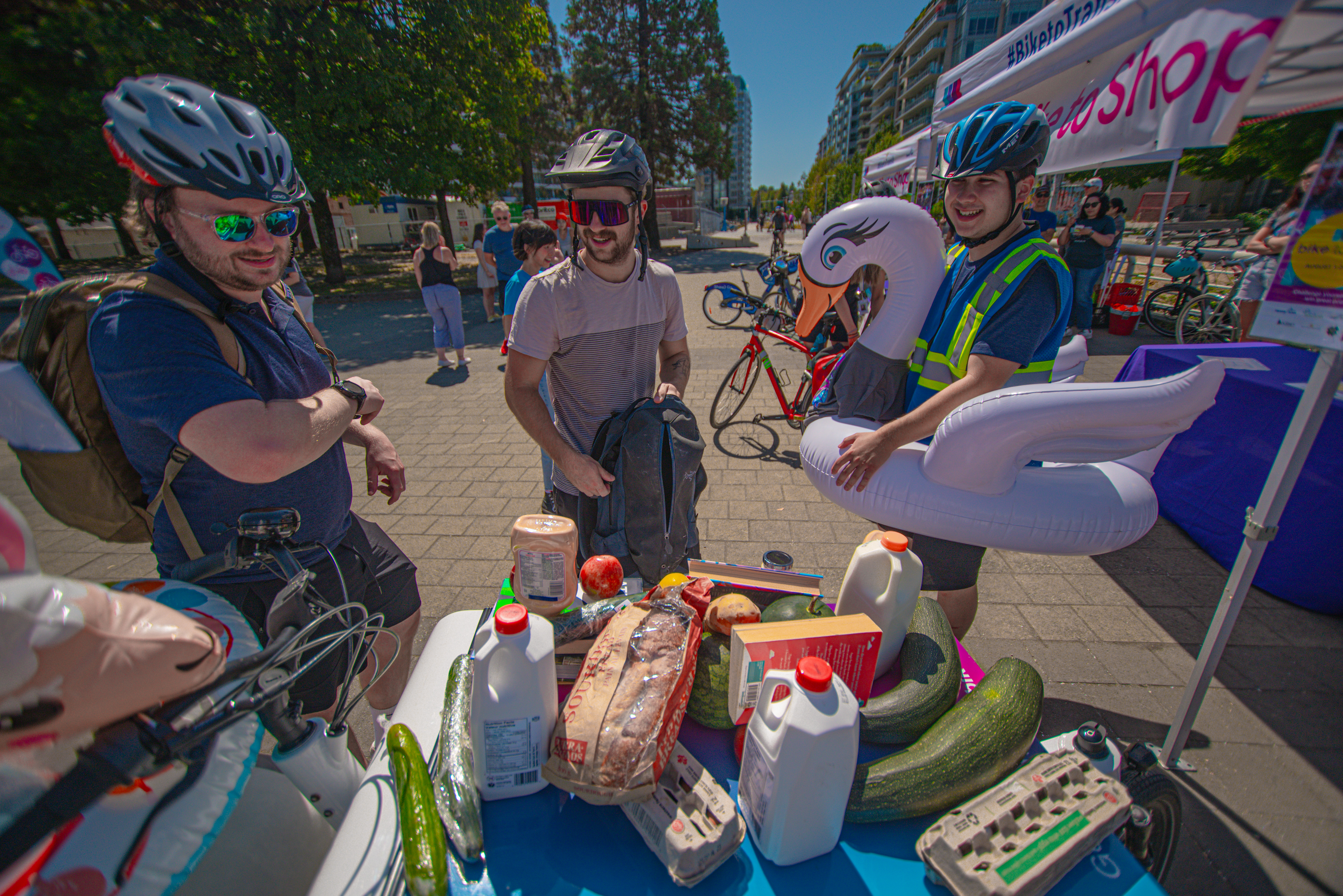 Three people from different teams prepare to put items in their bags at the Bike to Shop Challenge.